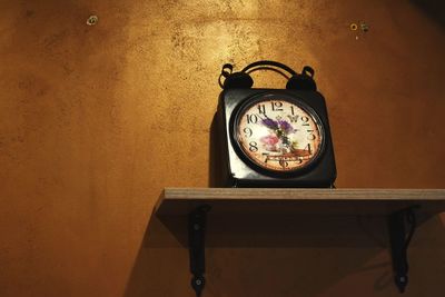 Close-up of clock on table against wall