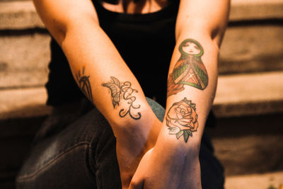 Midsection of woman with tattoos sitting on steps