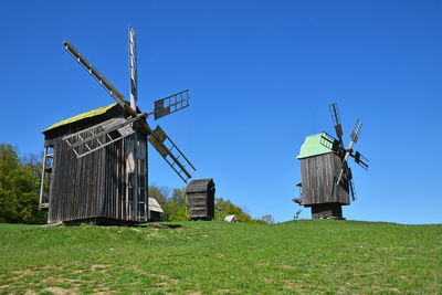 Low angle view of old-fashioned wind turbines on grassy hill