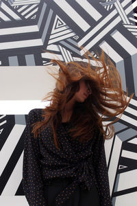 Portrait of young woman standing against wall