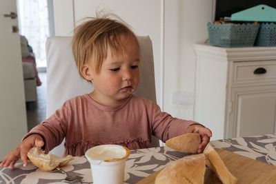 Small girl sitting at the table and having breakfast