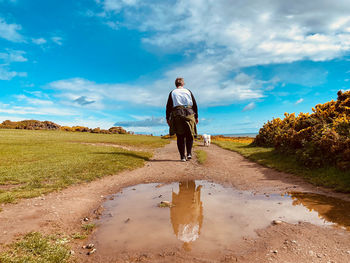 Rear view of woman walking against blue sky