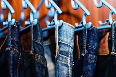 Close-up of jeans hanging on coathangers in store for sale