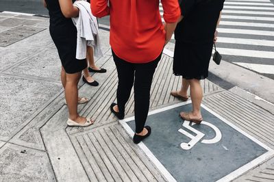 Low section of friends standing on footpath