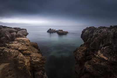 Rocks in sea against sky