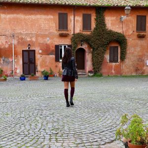 Rear view of woman walking on footpath against building