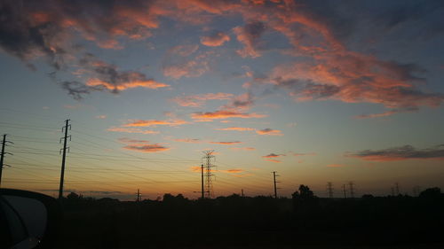 Silhouette electricity pylon against sky during sunset