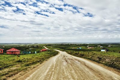 Road amidst field against sky