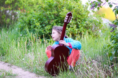 Rear view of girl sitting on field