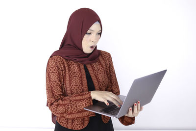 Midsection of woman holding smart phone against white background