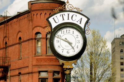 Low angle view of clock amidst buildings in city