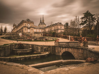 Bridge over river in city against cloudy sky