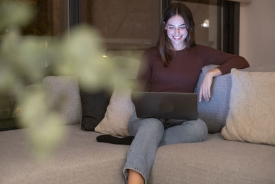 Portrait of young woman sitting on sofa at home