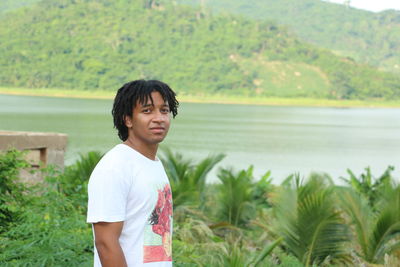 Portrait of young man standing against lake