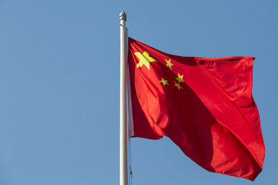 Low angle view of flag against clear blue sky