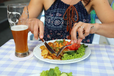 Midsection of woman eating food at table