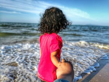 Cropped image of parent holding daughter hand at beach