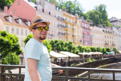 Portrait of man wearing sunglasses standing against railing