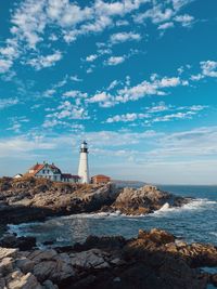 Lighthouse by sea against sky