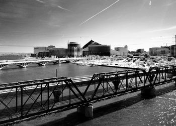 Bridge over river by buildings in city against sky