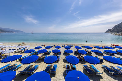 Italy, liguria, monterosso al mare, rows of deck chairs and umbrellas on sandy beach along cinque terre