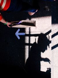 Low section of man with shadow on road