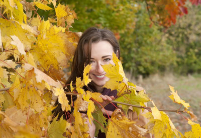 Portrait of woman wearing coat standing by trees in park during autumn