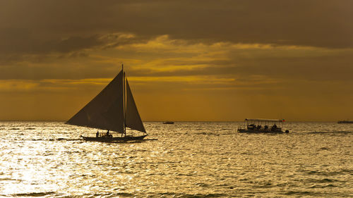 Sailboat sailing on sea against sky during sunset