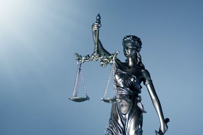 Low angle view of lady justice against clear blue sky