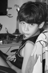 Black and white portrait of a quiet serious child in her bedroom looking at the camera. 