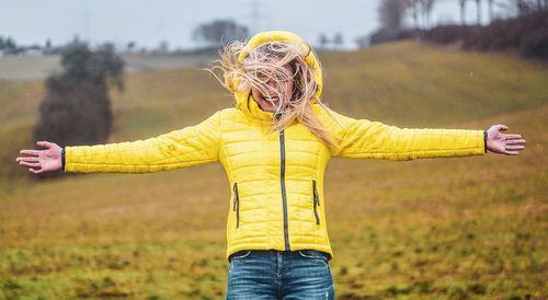 Midsection of woman with umbrella standing on field