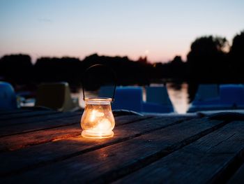 Close-up of illuminated lamp on table against sky at sunset