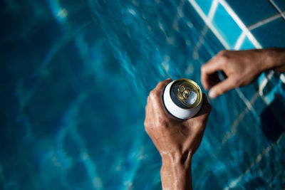 Selective focus white beer can in hand. man is soaking in the pool with an open beer can relax 