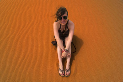 High angle view of woman sitting on sand dune