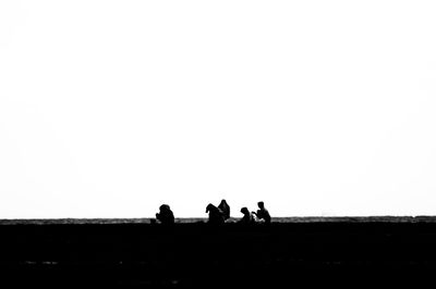 Silhouette people on field against clear sky