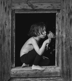 Side view of girl sitting on wooden door