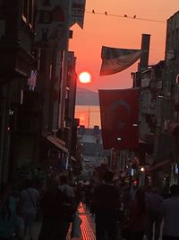 Group of people walking on city street at sunset