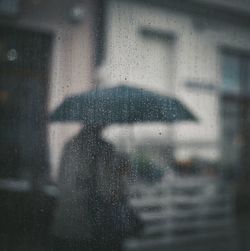 Woman seen through wet window in rainy season