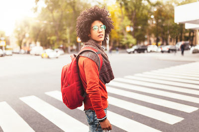 Young woman looking away while standing on city street