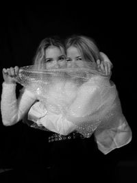Portrait of woman holding mask against black background