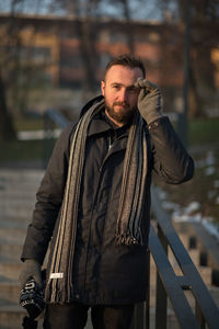 Portrait of young man in warm clothing moving down on steps at park