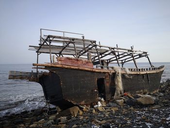 Metal structure on beach against clear sky