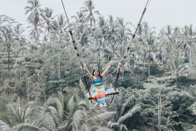 Young pretty asian woman is swinging on the cliff of the jungle in ubud, bali.