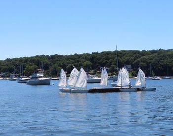 Sailboats in lake against clear blue sky