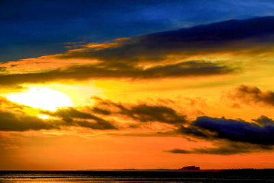 Scenic view of sea against dramatic sky during sunset