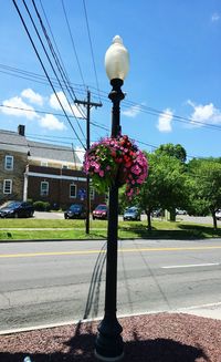 Street light by road against cloudy sky