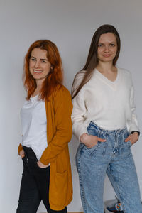 Happy two women in their 20s 40s over white wall. employees in casual outfit looking at the camera