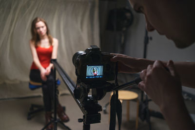 Midsection of man photographing woman in studio