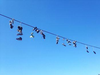Low angle view of shoes hanging against clear sky