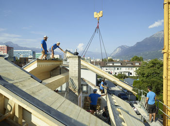 Blue-collar workers at construction site standing on rooftop